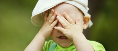 Jongetje speelt verstoppertje Kleine ogenschijnlijk vrolijke jongen speelt verstoppertje