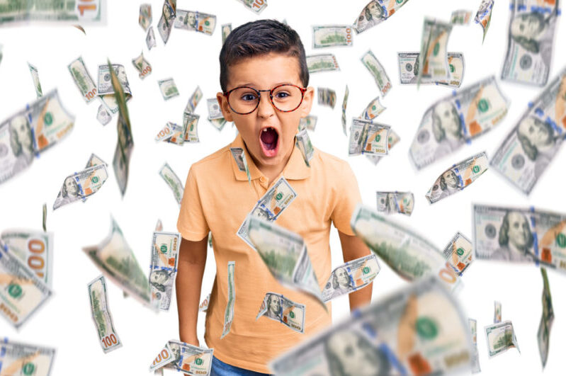 Jongetje druk, geld wordt over hem uitgestrooid.