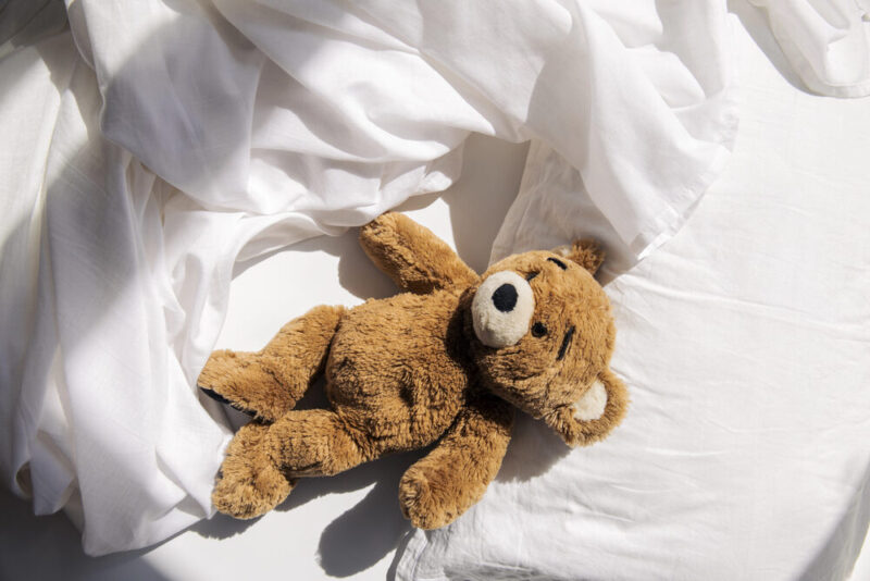 Een teddybeer in een leeg bed. Een treurig beeld voor het levend verlies van kinderen die uithuisgeplaatst zijn.
